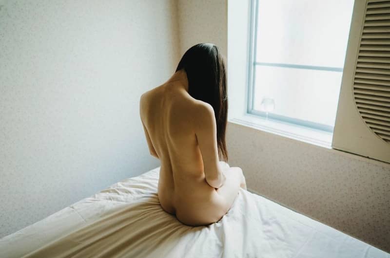 【場所】ただベッドで静かに黄昏れている裸の女性の画像